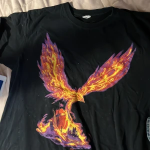 Trans-Siberian Orchestra tour t-shirt XL - Svart band-tshirt från Trans-Siberian Orchestra Winter Tour 2011. Stor färgglad fenix-tryck i lila, orange och gult på framsidan och turnédatum på baksidan. Klassisk passform med korta ärmar och rund hals. Perfekt för dig som gillar rock och coola tryck.