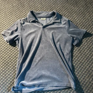 Blå pikétröja i frotté från Kappahl - Säljer en blå pikétröja i mjuk frotté från Kappahl. Tröjan har korta ärmar och klassisk krage. Tröjan är i storlek 152 och passar perfekt till sommar. 