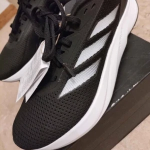Adidas Duramo SL M löparskor storlek 42,5  - Säljer ett par svarta Adidas Duramo SL M sneakers med vita detaljer och klassiska tre ränder på sidan. De passa inte och jag tappa bort kvittot så jag kunde inte lämna tillbaka dem så jag säljer dom nu för 470kr istället för 700kr orginal pris de är helt sprillans nya! Och de är bra för vardagliga livet och träningen! STORLEK 42,5 Dom finns i Linköping 