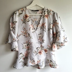 Blommig linneblus Zara - Superfin blommig omlottblus från Zara Woman i duvblått med vida trekvartsärmar och v-ringning. Blusen har ett romantiskt blommönster i rosa, vitt och grönt. Perfekt för vår och sommar när du vill känna dig extra söt. 100% linne, perfekt skick.