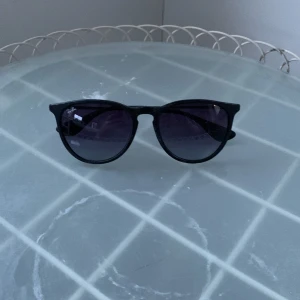 Svarta solglasögon från Ray-Ban  - Klassiska svarta solglasögon från Ray-Ban med rundade bågar och mörka glas. Snygg och tidlös modell  som passar till många stilar. Tillverkade i 🇮🇹  Modell Erika. Inget fodral med