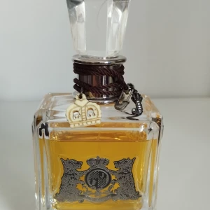 Eau Couture by Juicy Couture parfym 100 ml - Juicy Couture parfym i en lyxig, fyrkantig glasflaska med silverfärgad emblem och detaljer som en krona och bokstavsberlock.. Top notes are Mandarin Orange, Passionfruit, Watermelon and Green Apple; middle notes are Tuberose, Lily and Rose; base notes are Woodsy Notes, Caramel, Vanilla and Patchouli