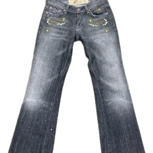 Bootcut jeans med nitar från 7 For All Mankind - Mörkgrå bootcut jeans från 7 For All Mankind med snygga nitar och gröna stenar på fram- och bakfickor. Nypris 2000kr