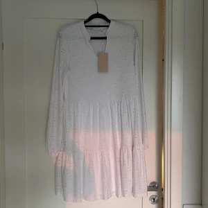 Vit broderad klänning från Vila - Superfin vit klänning från Vila med broderade detaljer och lång ärm. Klänningen har v-ringning, lätt volang i kjolen och är tillverkad i bomull. Perfekt för sommarens tillfällen och har en luftig, normal passform. Endast testad!💞