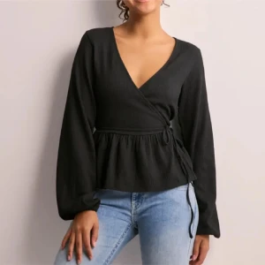 svart omlottopp med långa ärmar - snygg  svart omlottopp med v-ringning och långa ärmar 💕toppen har en knytning i sidan som ger den en fin passform ✨