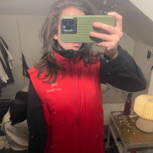 Röd väst från Arc'teryx - Säljer en snygg röd väst från Arc'teryx. Västen har en dragkedja framtill och är perfekt för lager-på-lager. Den är Fair Trade-certifierad och har en stilren design. Inköpt på Arcteryx hemsida i höstas och använd 1-2 gånger! Nypris 2200 