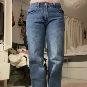 Mid/low waist baggy jeans - Snygga blå jeans med rak passform och klassisk femficksdesign. De har en knapp och dragkedja framtill. Perfekta för en avslappnad stil. Jag är 155cm och dem är ca 7 cm för långa för mig. Skriv för fler bilder.