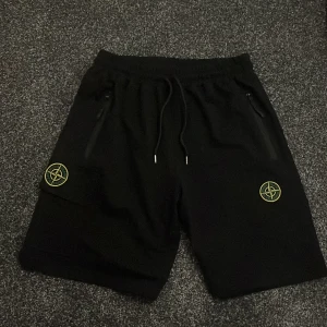 Svarta shorts från Stone Island - Snygga svarta shorts från Stone Island med broderad logga på benet. De har praktiska dragkedjor och snörning i midjan för en bekväm passform. Perfekta för en stilren look.