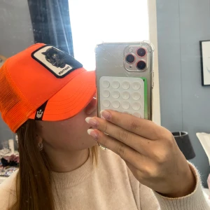 Orange caps med pantermotiv (Goorin bros) - Snygg orange caps med ett broderat pantermotiv på framsidan. Capsen har ett nätmaterial på baksidan för bättre ventilation och en justerbar rem för perfekt passform.