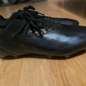 Svarta fotbollsskor med blå detaljer - Säljer ett par ADIDAS X CRAZYFAST .1 FG NIGHTSTRIKE - SVART ELITE. Dessa är designade för att vara lättviktiga. De har knappt används max 5 gånger och ordinarie pris ca 3000kr.