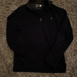 Svart tröja från Polo Ralph Lauren - Snygg marinblå tröja från Polo Ralph Lauren med quater/half dragkedja och broderad logga på bröstet. Perfekt för Vinter. Storlek S, riktigt bekväm och som nytt 9/10. Ny pris 1900kr fast jag säljer för 999kr