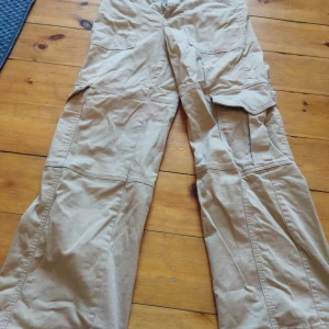 Beige cargobyxor från Stay - Säljer ett par beige cargobyxor från Stay. Byxorna har flera praktiska fickor och en avslappnad passform. Perfekta för en casual look. De är tillverkade i ett slitstarkt material och har en klassisk design.