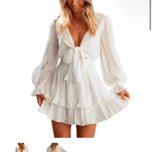 Vit klänning med knyt och volang - Säljer en söt vit klänning med knyt framtill och volangdetaljer. Klänningen har långa ärmar och en v-ringad design som ger en elegant touch. Perfekt för sommarens alla tillfällen!