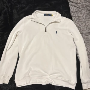 Vit tröja med dragkedja från Ralph Lauren - Säljer en stilren vit tröja från Ralph Lauren med dragkedja och broderad logga på bröstet. Tröjan har långa ärmar och en klassisk krage. Storlek S sitter bra på dig runt 180cm. Skriv vid intresse.