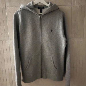 Grå hoodie från Polo Ralph Lauren - Säljer min snygga och sköna Ralph lauren hoodie i 10/10 skick då den inte passar längre. Den är storlek 170 som är som en stor s i vuxen storlek, skriv vid frågor.