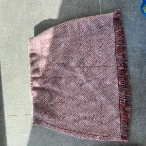 Mönstrad kjol med fransar från Zara - Säljer en mönstrad kjol i röd och vit med fransar längs nederkanten. Kjolen har en rak passform och har även en matchande top jag säljer! 