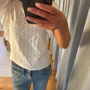 Vit blus från Zara - Säljer en söt vit blus från Zara med broderade hålmönster och volangdetaljer på ärmarna. Endast använd fåtal gånger