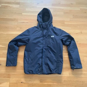 2 i 1 mörkblå jacka från Helly Hansen  - Säljer en mörkblå 2 i 1 jacka från Helly Hansen. Jackan är i storlek M, är endast använd 3 gånger och består av en värmejacka samt en skaljacka. Finns det frågor är det bara att skriva