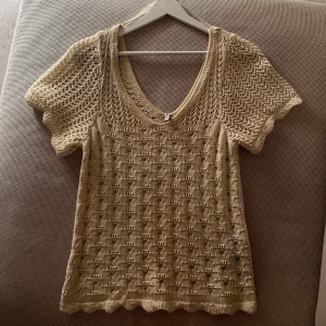 Beige stickad topp - Säljer en beige stickad topp med v-ringning och korta ärmar. 