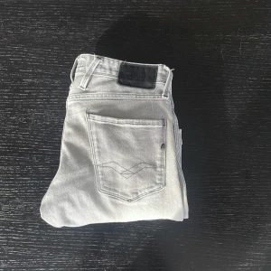 Grå Replay jeans - Snygga grå jeansbyxor med klassisk femficksdesign och en svart läderpatch på baksidan. Perfekta för en stilren look. De har en rak passform och är tillverkade i ett slitstarkt material. 