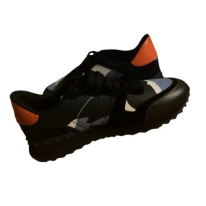 Valentino Garavani Rockrunner med kamouflagemönster -  Valentino Garavani sneakers med ett coolt kamouflagemönster i blått, svart och vitt. Lite använda som man ser men nästan oanvända, storlek 43. Vad som medföljer: Skor, Extrasnören, Dustbag och kartong (lite skadad), Passar även 44 (ganska stora i storleken), 