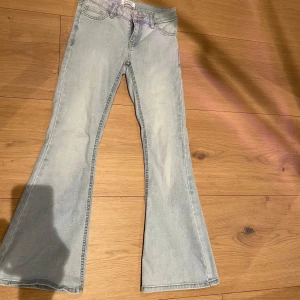 Ljusblå bootcut jeans från Lindex - Säljer ett par ljusblå bootcut jeans från Lindex. De har en klassisk femficksdesign och är tillverkade i ett mjukt denimtyg. Perfekta för en avslappnad stil med en touch av retro.