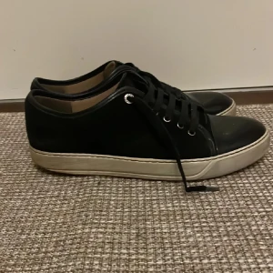 Svarta sneakers från Lanvin - Snygga svarta sneakers från Lanvin med vit sula och klassisk snörning. Perfekta för en stilren look.