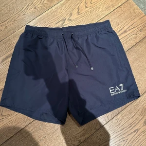 Blåa badbyxor från Emporio Armani - Snygga blåa badbyxor från Emporio Armani med elastisk midja och snörning. Med fickor på sidorna 