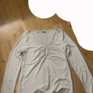 Vit ribbad topp - Säljer en stilren vit ribbad topp med långa ärmar.      v ringad och har ett ”hål” i mitten. Lätt att stylea 