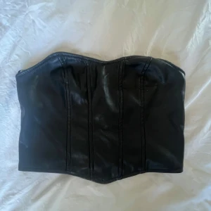 Svart korsett i skinnimitation - Snygg svart korsett i skinnimitation med en stilren design. 