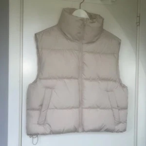 Beige dunväst med dragkedja - Säljer en  beige dunväst från bikbok.