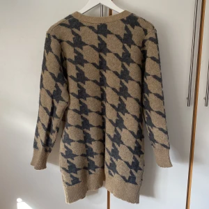 Beige och grå kofta från Pure Instinct - Säljer en beige kofta med grått snyggt hundtandsmönster från Pure Instinct. Koftan har långa ärmar och är en  öppen modell utan knäppning. Väldigt mjukt och lent material. Längd 85 cm. Använd 1-2 gånger. 