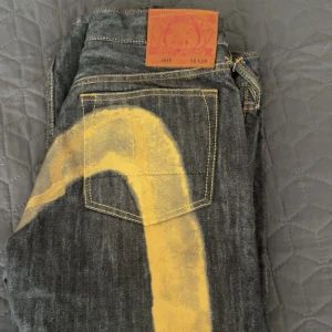 Evisu jeans med guldiga detaljer  - As snygga jeans, bara använt tre gånger sen jag köpte dom. Dom är grå svarta med guld detaljer och tryck på baksidan💕