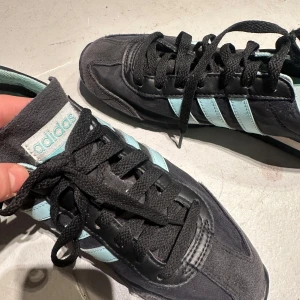 Svarta och ljusblå sneakers från Adidas - Snygga svarta sneakers med ljusblå detaljer från Adidas. Skorna har klassiska tre ränder på sidan och snörning framtill. Perfekta för en avslappnad stil. #adidas #samba #spezial