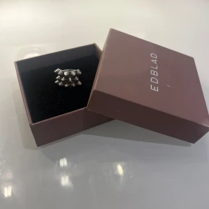 Silverfärgad ring från Edblad - Snygg silverfärgad ring från Edblad med ett unikt designmönster av små spetsiga detaljer. Perfekt för att ge en edgy touch till din stil. Kommer i originalförpackning.
