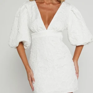 Vit klänning med puffärmar - Säljer en elegant vit klänning med v-ringning och puffiga trekvartsärmar. Klänningen har en figursydd midja. Ny med prislapp endast testad.💕