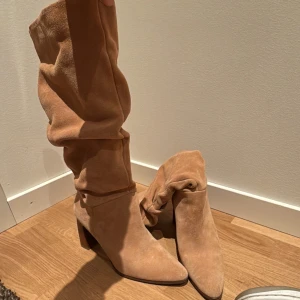 Beige mocka boots med klack - Snygga beige boots i mocka med hög klack, ca 8 cm. Storlek 38, har använt de nån gång men de ser ut som nya. Köpte för 1300 