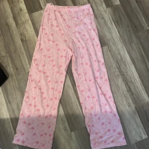 Rosa Hello Kitty pyjamasbyxor från H&M - Säljer ett par ljusrosa pyjamasbyxor från H&M med Hello Kitty-motiv i rosa och vitt. Byxorna har resår i midjan och är raka i modellen, perfekta för mysiga hemmakvällar.