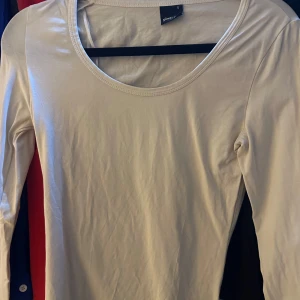 Vit långärmad topp från Gina Tricot - Säljer en enkel och stilren Vit långärmad topp från Gina Tricot. Toppen har rund halsringning och är tillverkad i ett mjukt material som passar perfekt till många olika outfits.