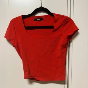 Röd croppad topp från Bikbok - Säljer en röd croppad topp från Bikbok  med rundad urringning och korta ärmar. Perfekt för att addera färg till din outfit. Enkel och stilren design som passar till mycket.