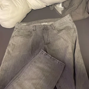 Grå jeansbyxor från Vaillent - Säljer ett par grå jeansbyxor från Vaillent i storlek XL. Klassisk femficksmodell med dragkedja och knapp framtill. Byxorna har en rak passform och är tillverkade i ett slitstarkt jeanstyg.