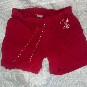 Vintage Röda Snoopy-shorts💫 - Röda shorts med vit Snoopy märke på ena benet och snörning i midjan med vita prickar. Mjukt bomullsmaterial och avslappnad passform-sommardagar eller som mysplagg. 