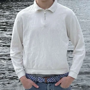 Vit långärmad pikétröja från Zara - Säljer en stilren vit långärmad pikétröja med krage och dragkedja vid halsen. Perfekt för en clean och avslappnad look. Passar till jeans eller chinos.