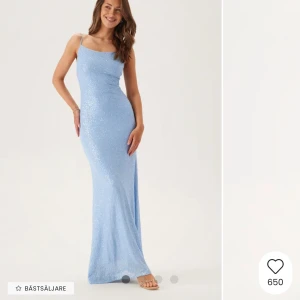 Ljusblå glittrig långklänning från Bubbleroom - Supersnygg ljusblå långklänning med glittrigt tyg och smala axelband. Klänningen har öppen rygg med knyt och en figurnära passform. Perfekt för bal eller festliga tillfällen när du vill sticka ut.