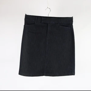 Svart jeanskjol från Lee  - Säljer en svart jeanskjol från Lee i klassisk rak modell. Kjolen har hällor för bälte och diskreta fickor fram. Materialet är en mix av bomull, polyester och spandex för lite stretch. Perfekt till dig som gillar enkel och stilren denim.