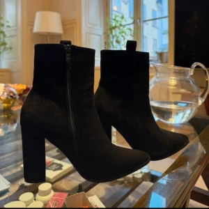 Svarta boots med klack - Säljer ett par svarta boots i mocka med hög klack och spetsig tå. Skorna har dragkedja på sidan och är endast använda en gång!                                           Klackhöjd: 8 cm