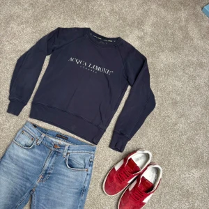 Mörkblå sweatshirt från Acqua Limone - Säljer en mörkblå sweatshirt från Acqua Limone med tryck på både bröstet och ryggen. Tröjan har rund halsringning och långa ärmar. Perfekt för en avslappnad stil. Storlek S.