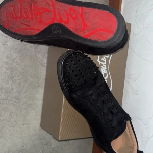 Svarta loubs med spikar - Säljer ett par svarta sneakers från Christian Louboutin med ikonisk röd sula. Skorna är använda mer än 8 gånger och kommer med en dustbag 