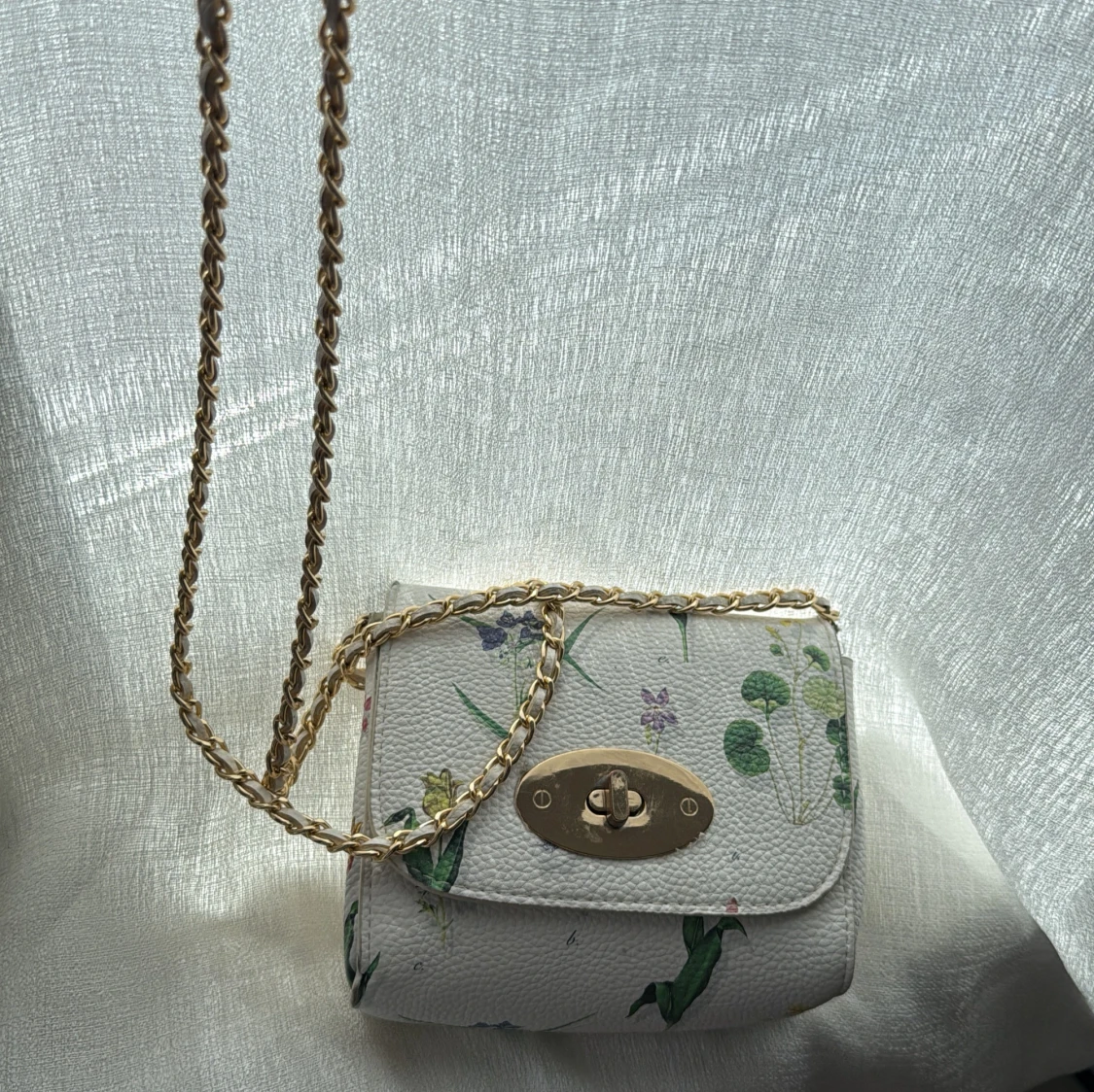 Vit axelväska med blommigt mönster och guldkedja