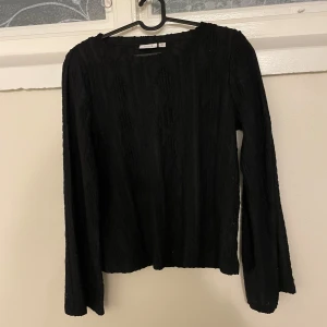 Svart spetsmönstrad topp från VILA - Säljer en svart långärmad topp från VILA med vackert spetsmönster och transparenta detaljer. Toppen har rund halsringning och är perfekt för att lyfta en outfit med sin eleganta look.